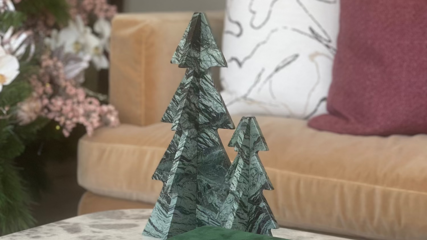 Decorative green tree sculpture on top of books with a living room background