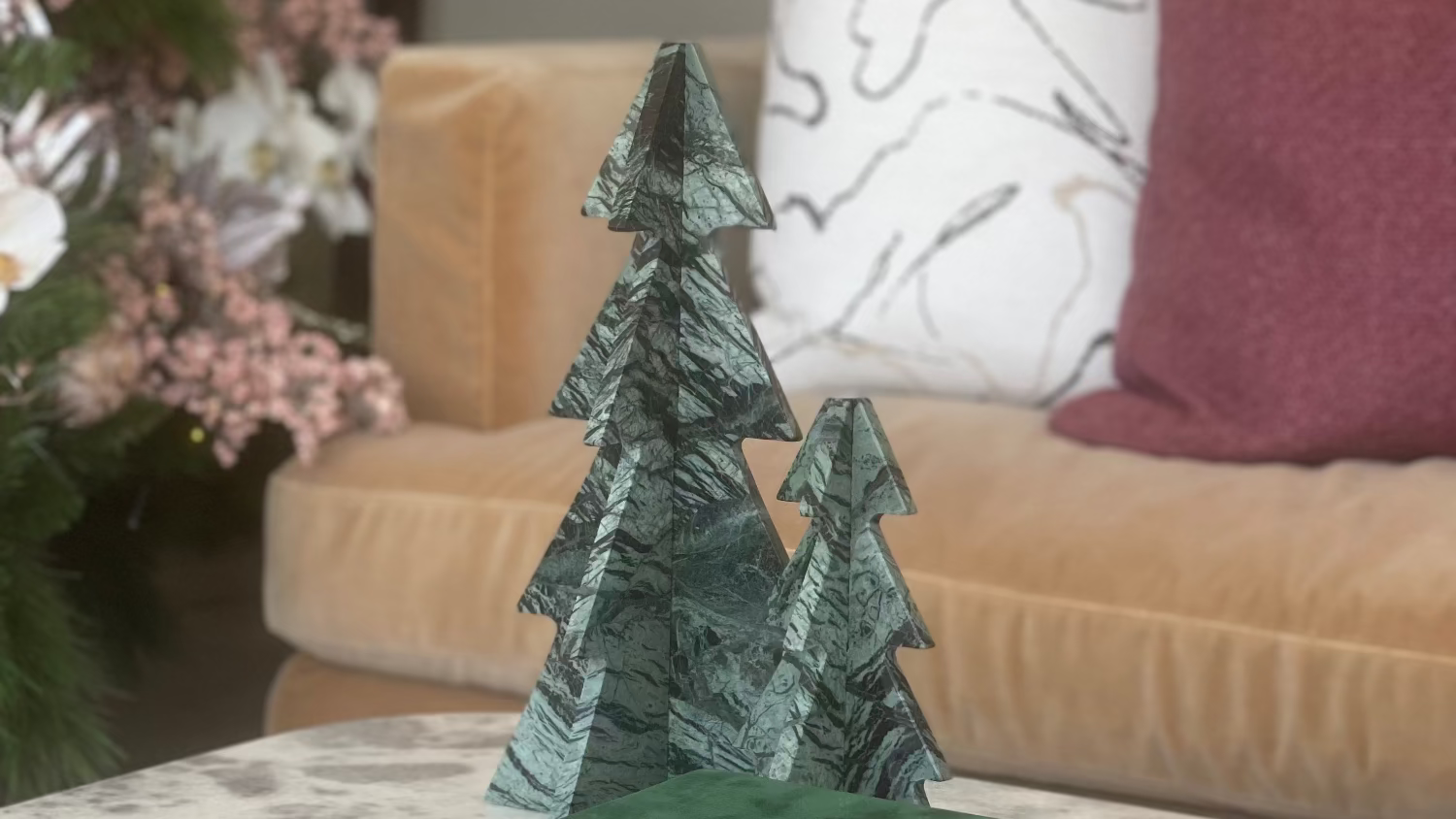Decorative green tree sculpture on top of books with a living room background