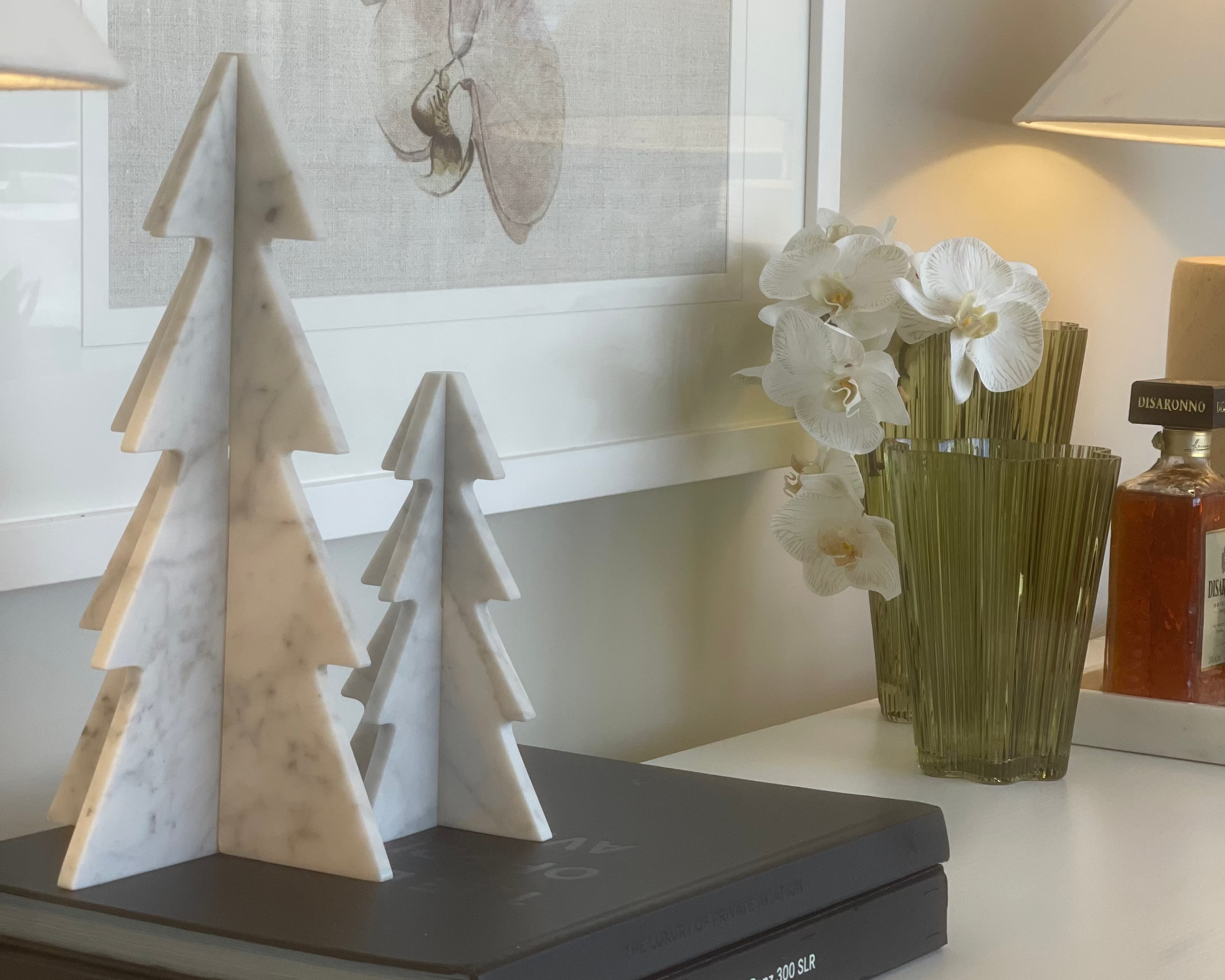 Decorative book with marble-like tree design on a shelf with a vase of flowers and artwork in the background.